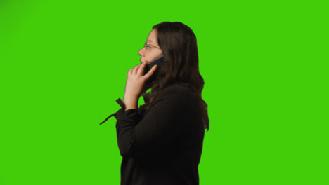 Side-View-Shot-Of-Businesswoman-Talking-On-Mobile-Phone-Walking-Across-Frame-Against-Green-Screen-1
